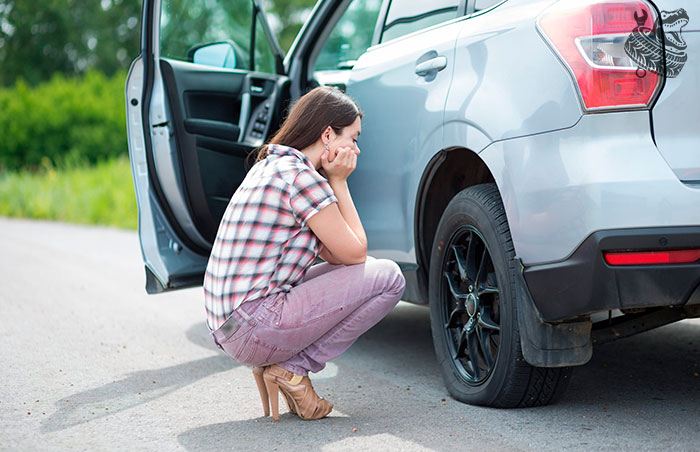 женщина не знает как заменить колесо автомобиля